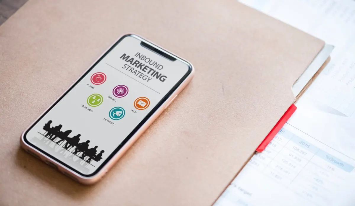 Celular com uma tela sobre estratégia de inbound marketing, sobre uma prancheta
