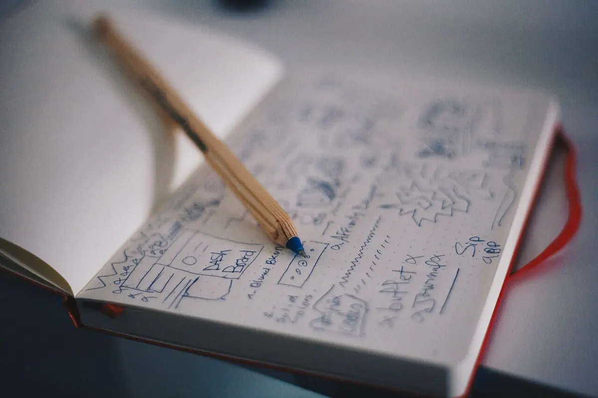 Caderno aberto com anotações e diagramas, ao lado de um lápis