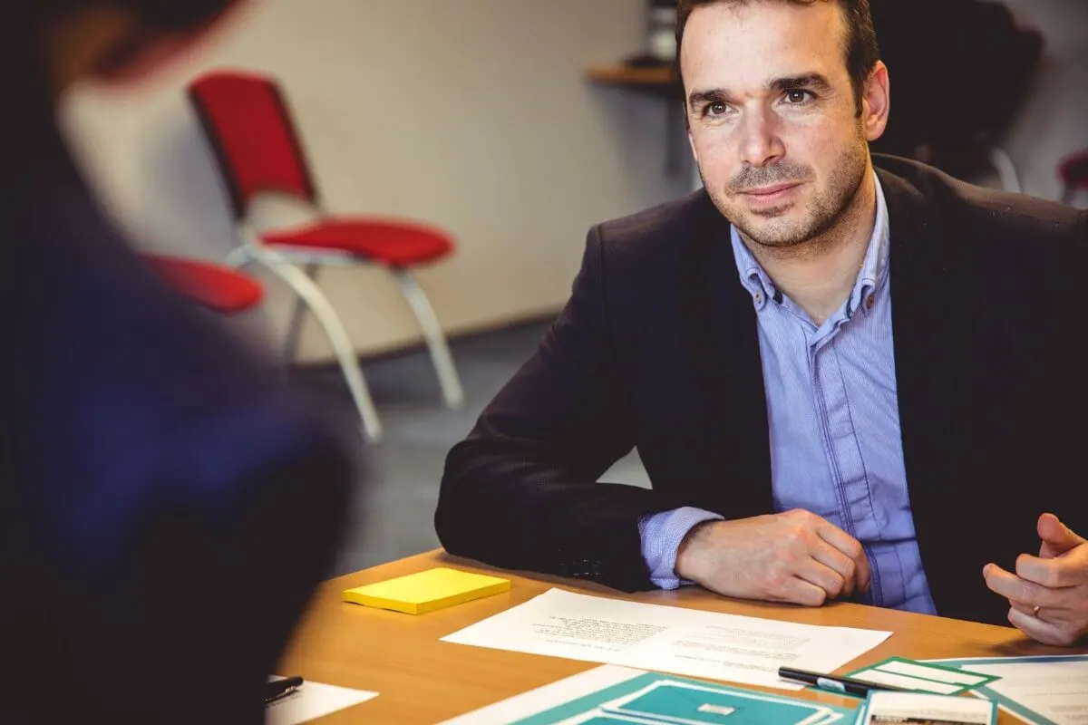 Homem de terno sentado a uma mesa de reunião