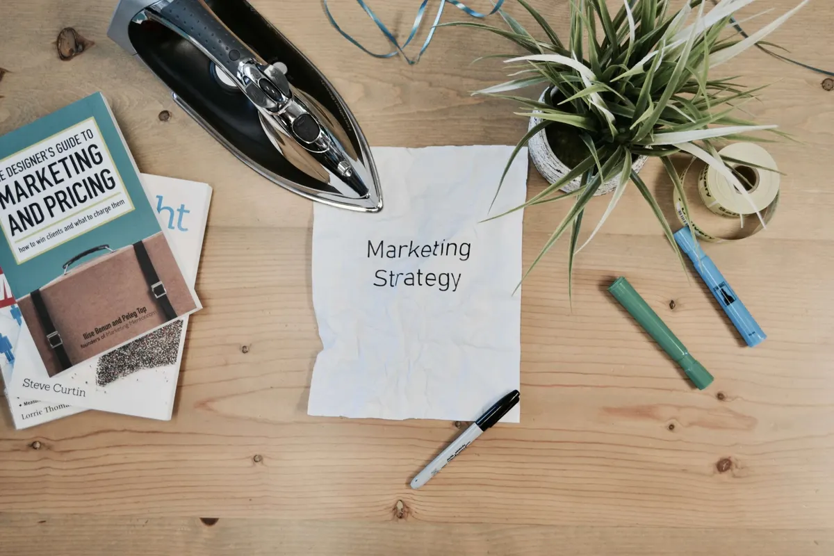 Livros de marketing, um caderno com a anotação Marketing Strategy e canetas sobre uma mesa
