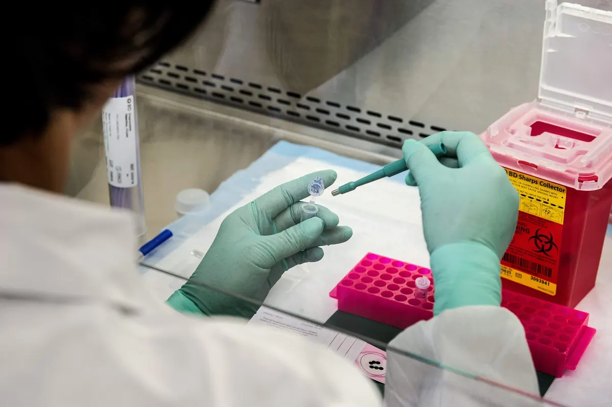 Profissional de laboratório manipula amostras em uma capela de segurança