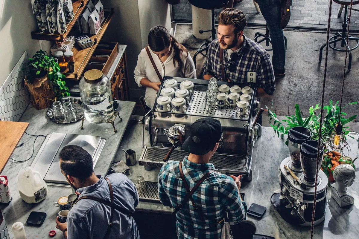 Vista de cima de uma cafeteria com baristas trabalhando