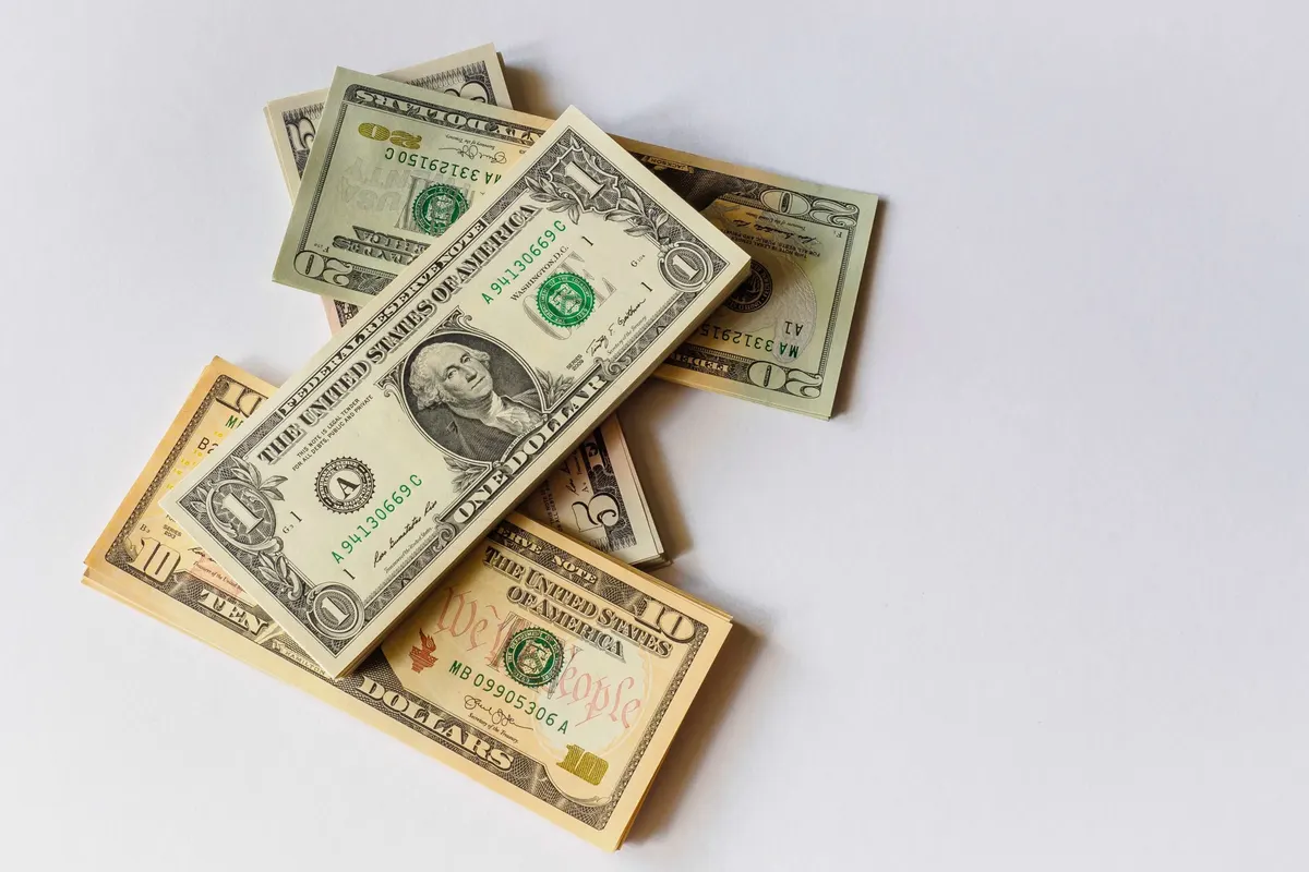 Notas de dólar espalhadas sobre uma superfície branca