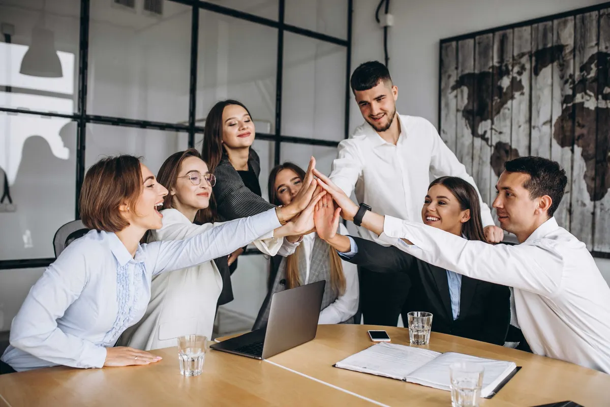 Equipe de escritório comemora batendo as mãos sobre uma mesa de reunião
