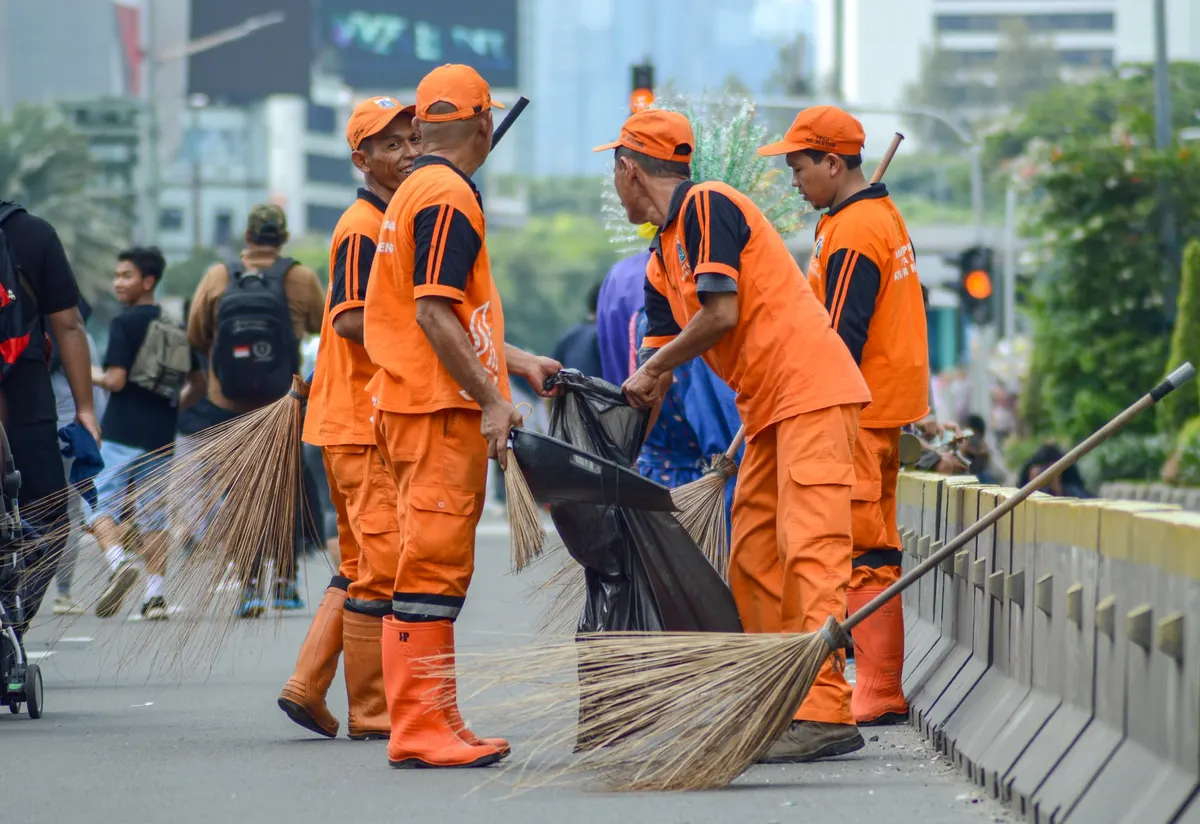 Garis de uniforme laranja varrem uma via