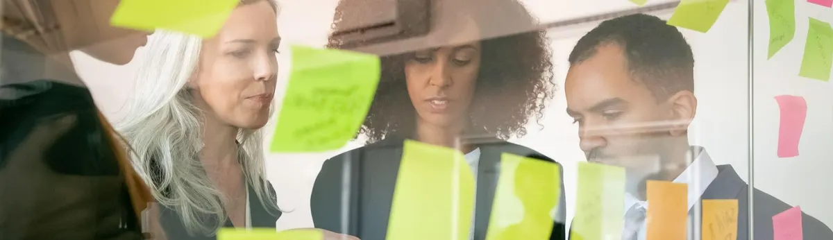 Capa de artigo do Liga Insights, com três pessoas diante de um vidro com post-its